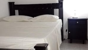 A bedroom with a bed, a nightstand, and a painting on the wall. - Taminaka Hostel (Santa Marta)