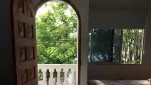 A room with a bed, a window, and a door leading to an outdoor area with potted plants. - Taminaka Hostel (Santa Marta)