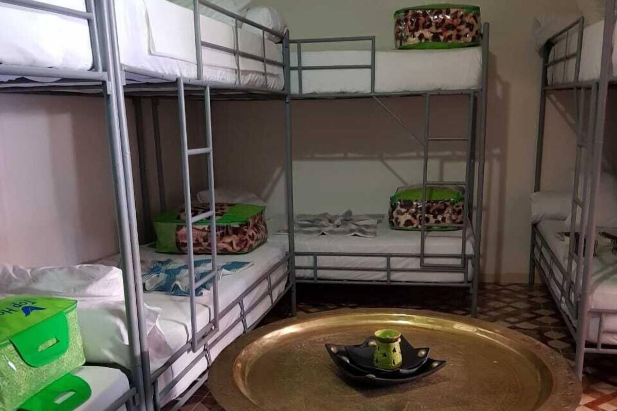 Un dormitorio con literas, una mesa redonda de madera con una bandeja y alfombra estampada.