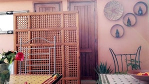 A room with a wooden partition, a metal chair, a table with a bowl, and decorative wall items. - Sun Hostel Marrakech (Marrakech)