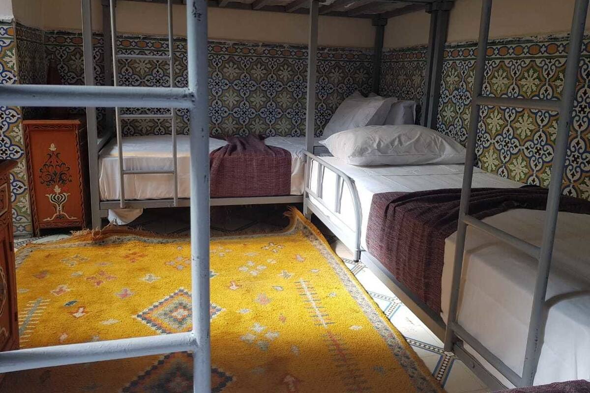 Un dormitorio con literas, un tapete estampado y un mueble decorativo.