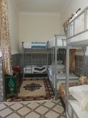A room with bunk beds, a patterned rug, and a decorative cabinet. - Sun Hostel Marrakech (Marrakech)