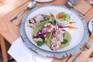 A plate of tacos with a side of guacamole and a small bowl of salsa.