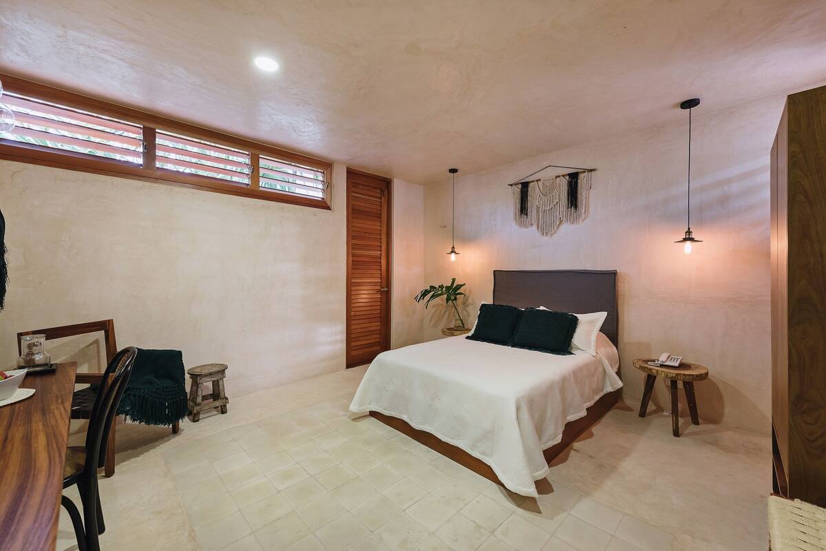 Un dormitorio con cama, mesitas de noche, escritorio y silla.