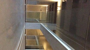 A modern interior with a glass railing, reflective surfaces, and a clean, minimalist design. - Rukaza El Golf (Santiago)