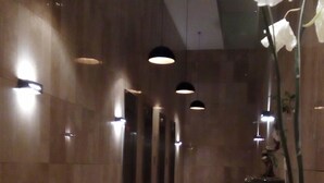 A modern lobby with a long corridor, potted plants, and pendant lighting. - Rukaza El Golf (Santiago)