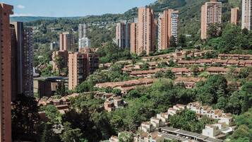 A residential area with a mix of high-rise and low-rise buildings, surrounded by greenery and hills in the background.