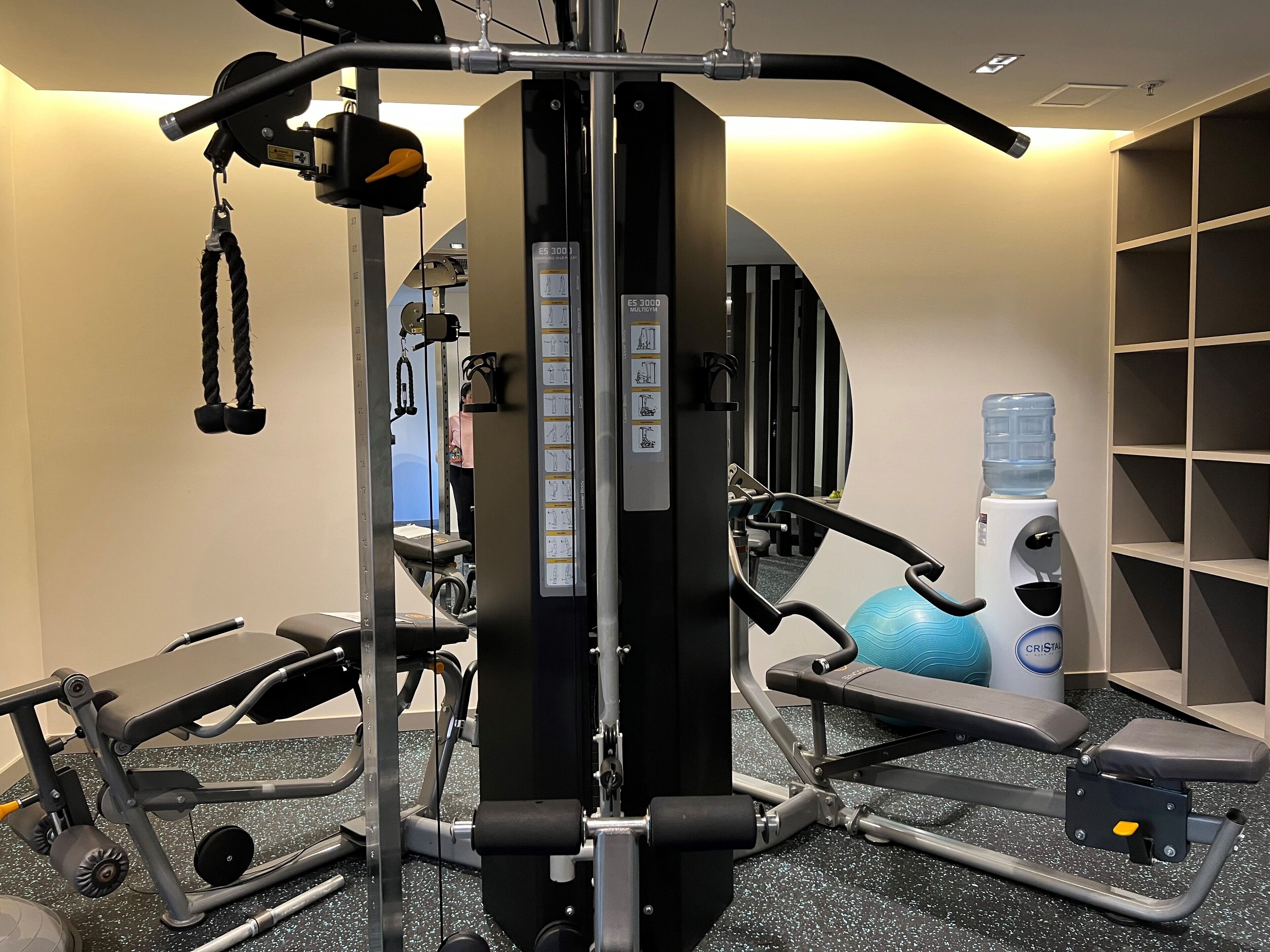 A gym with exercise equipment, a water dispenser, and a blue exercise ball.