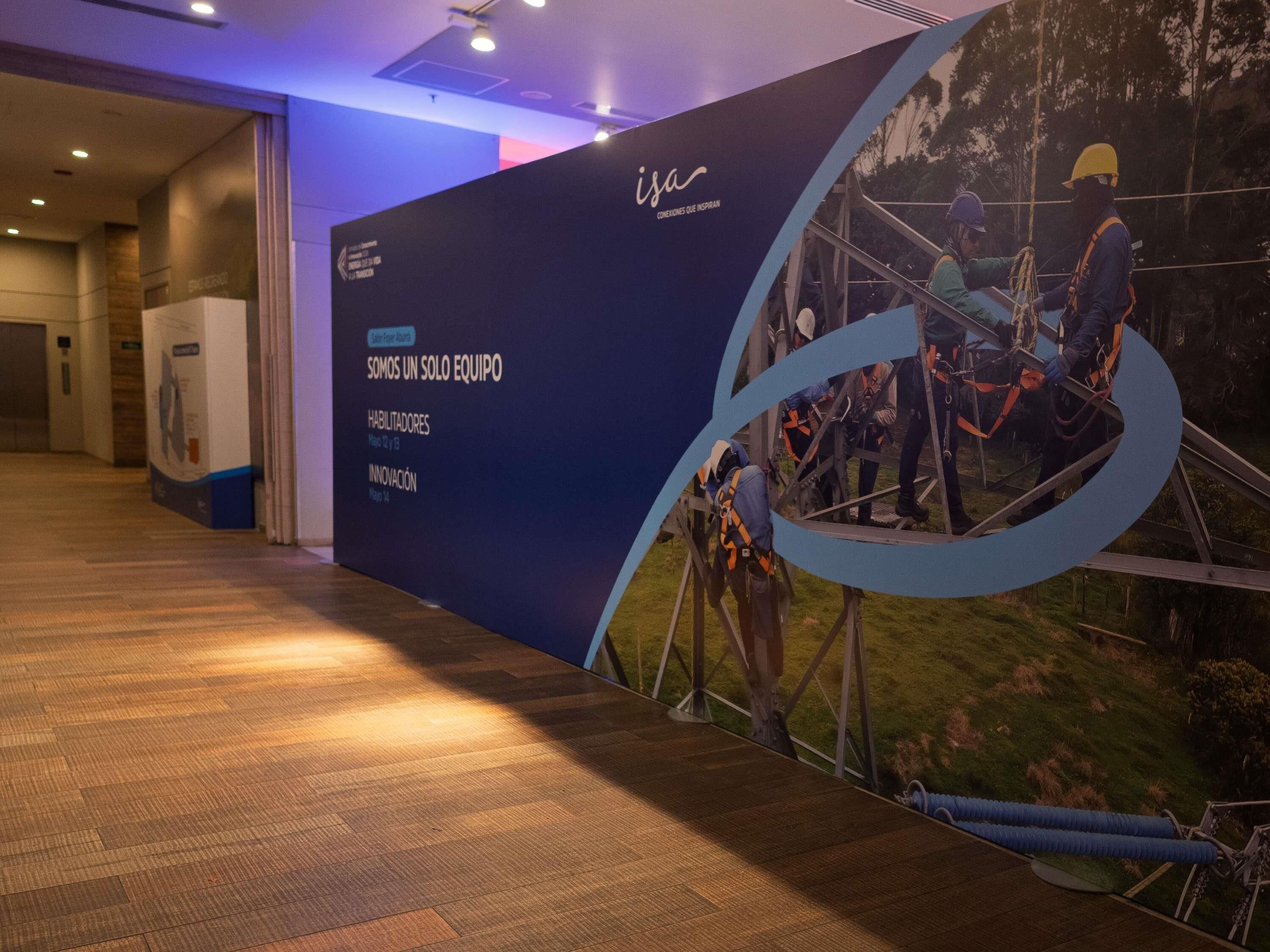 A conference room with a large poster on the wall, a wooden floor, and a door in the background.