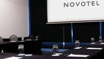 Ett konferensrum med en Novotel-skylt, namnskyltar och vattenglas på ett bord.