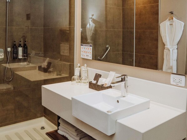 A modern bathroom with a large mirror, two sinks, a shower, and toiletries.