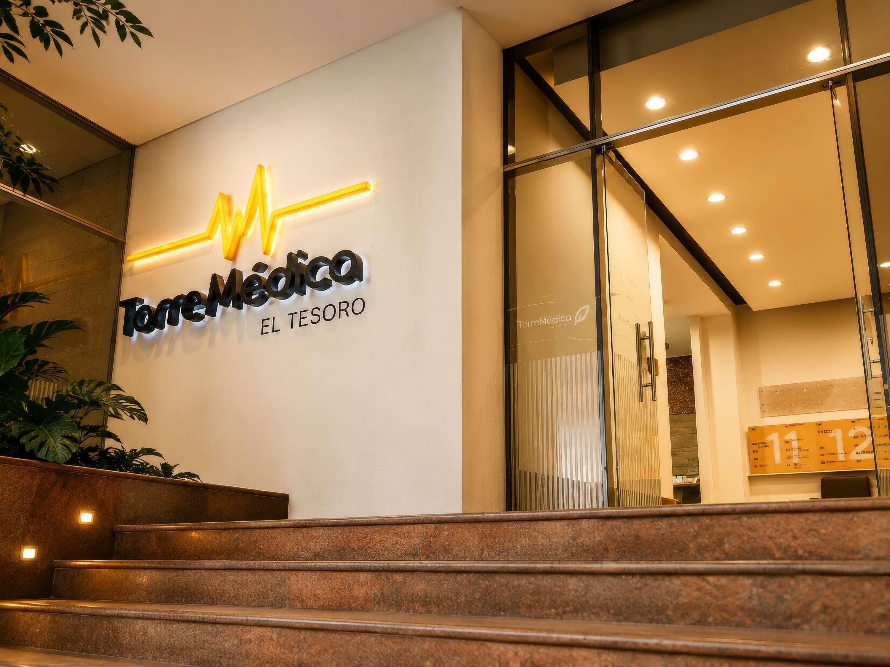 A modern building entrance with a sign reading 'Torremédica EL TESORO'.