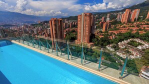 Una piscina con barrera de cristal, rodeada de edificios altos y vegetación.
