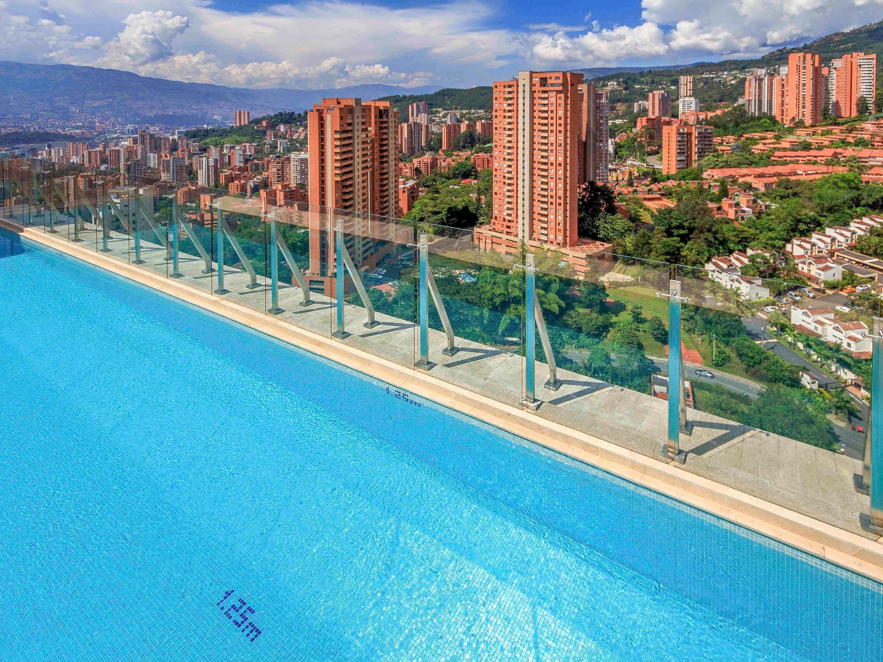 A swimming pool with a clear view of surrounding buildings and a distant mountain range.