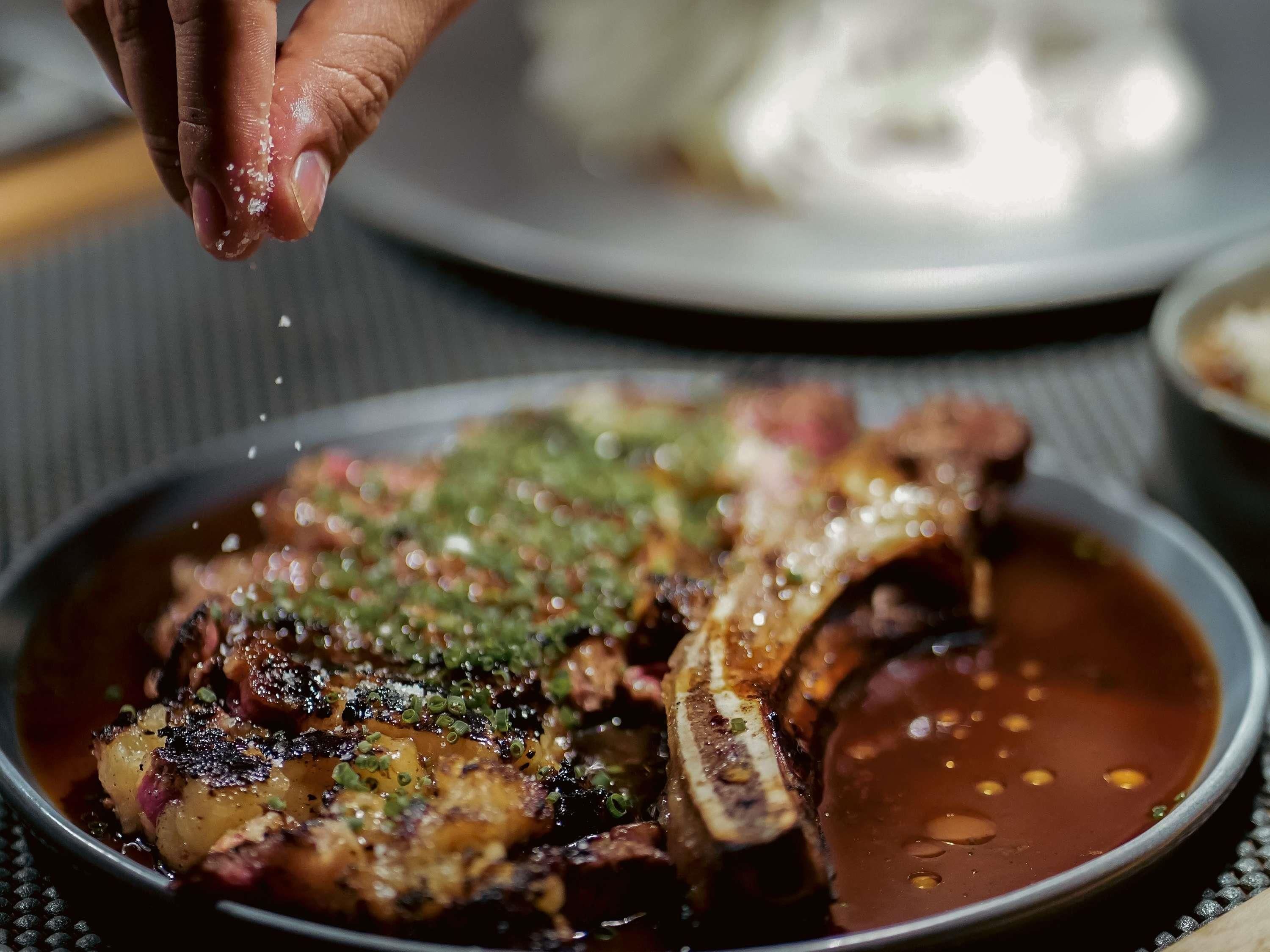 Un plato con carne y salsa, decorado con hierbas verdes.