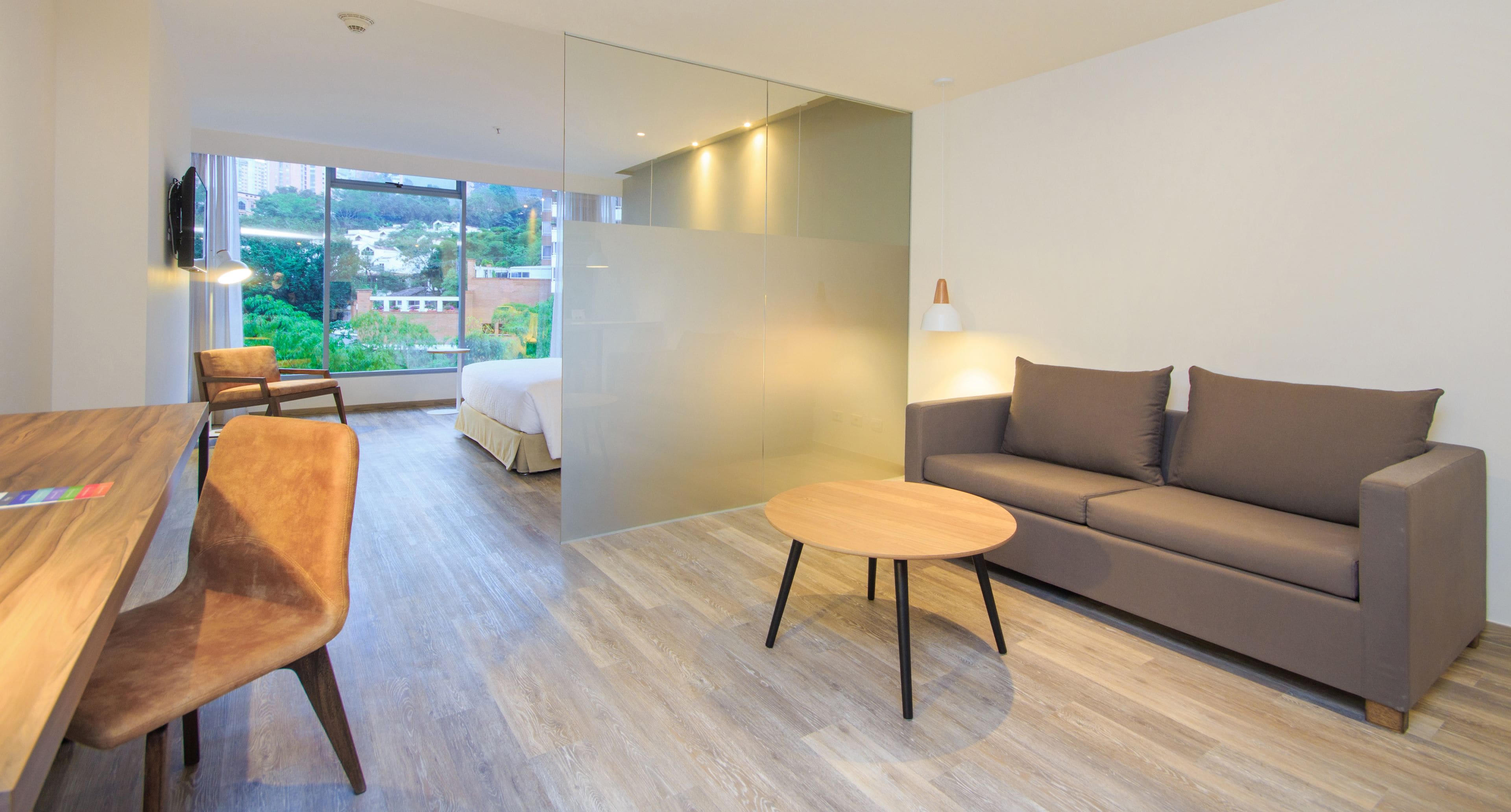 A modern living room with a sofa, a coffee table, and a dining area with a wooden table and chairs.
