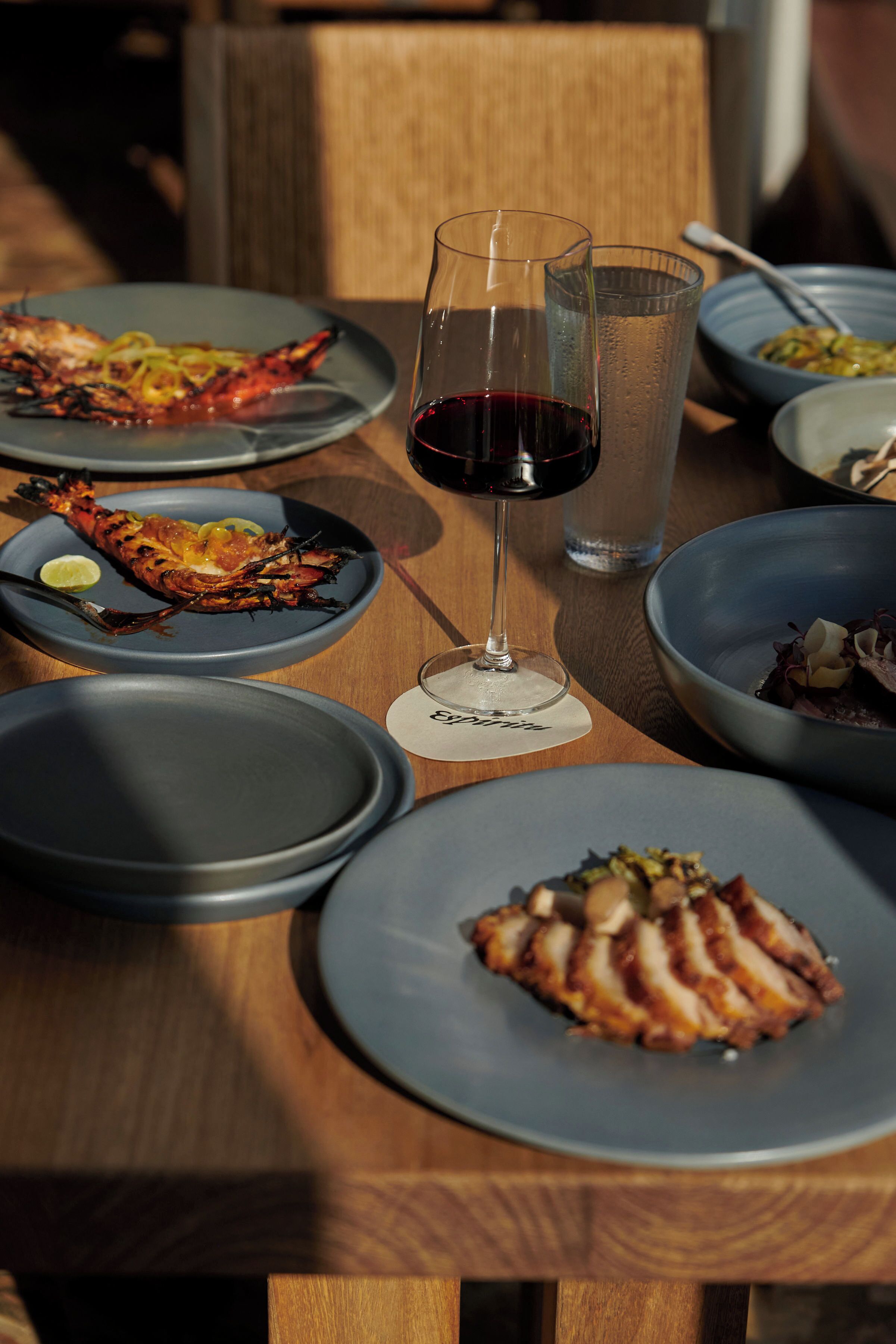 A dining table with various dishes and glasses of wine.