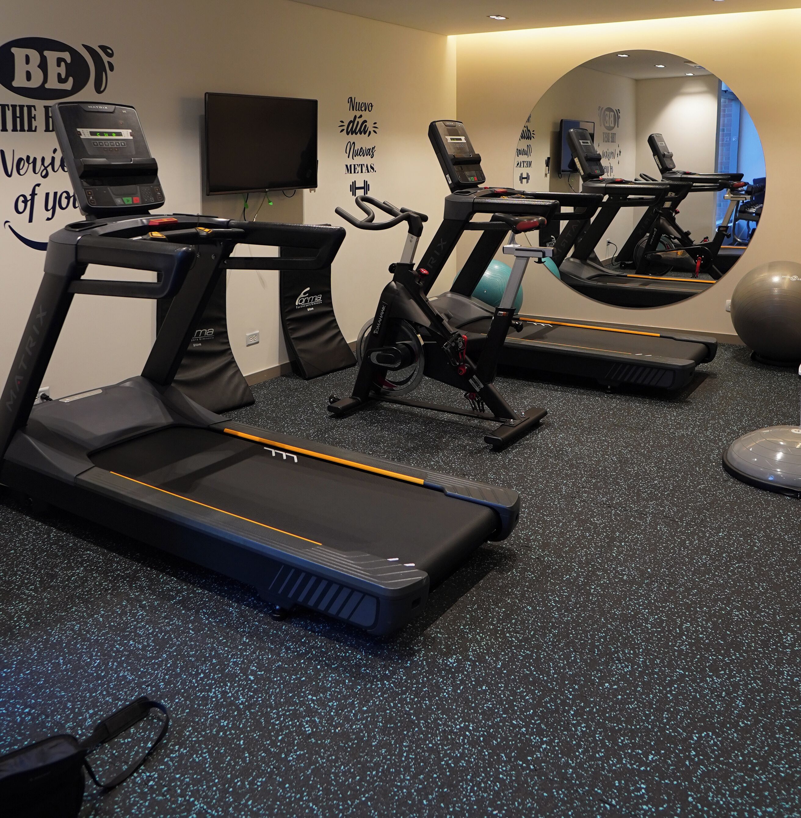 Ein Heimfitnessraum mit Laufbändern, einem Crosstrainer und einem stationären Fahrrad.