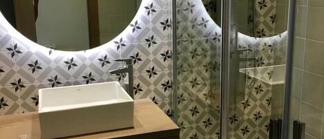 Un baño con un espejo grande, un lavamanos y azulejos con diseño.