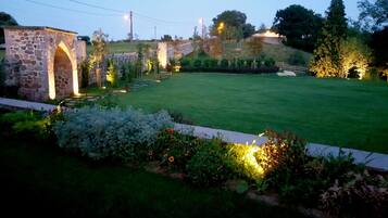 A well-maintained garden with a stone archway, a grassy lawn, and decorative lighting.