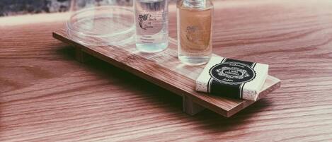 Una estantería de madera con tres botellas de vidrio y un recipiente de plástico transparente.