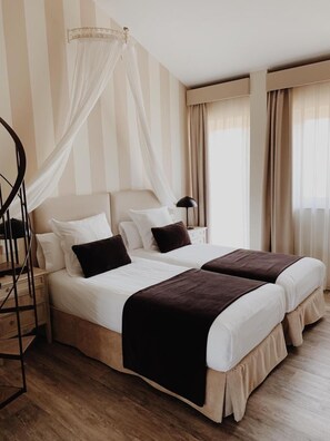 Une chambre d’hôtel avec deux lits, un lit à baldaquin, un plancher en bois et un escalier.