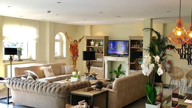 A modern living room with a sofa, coffee table, and decorative items. There is a television, a bookshelf, and a wall with motivational quotes. - La Fuentona De Santillana (Santillana del Mar)