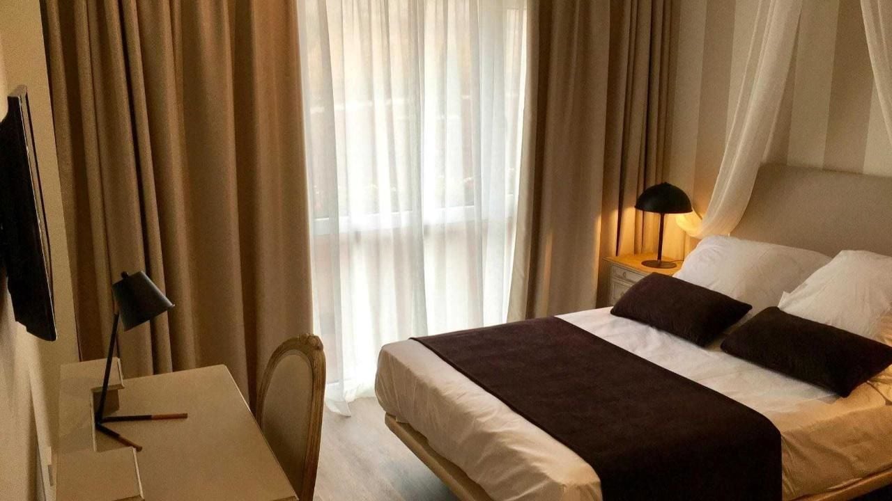 Une chambre d’hôtel avec un lit, un bureau, une chaise et une lampe.