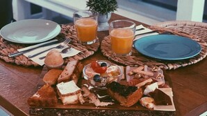 Bandeja de desayuno con diversos pasteles, frutas y jugos sobre una mesa de madera.