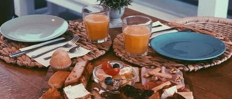 A breakfast tray with various pastries, fruits, and juices on a wooden table.