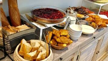 A buffet with various food items including bread, pastries, and a pie.