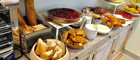 A buffet with various food items including bread, pastries, and a pie.