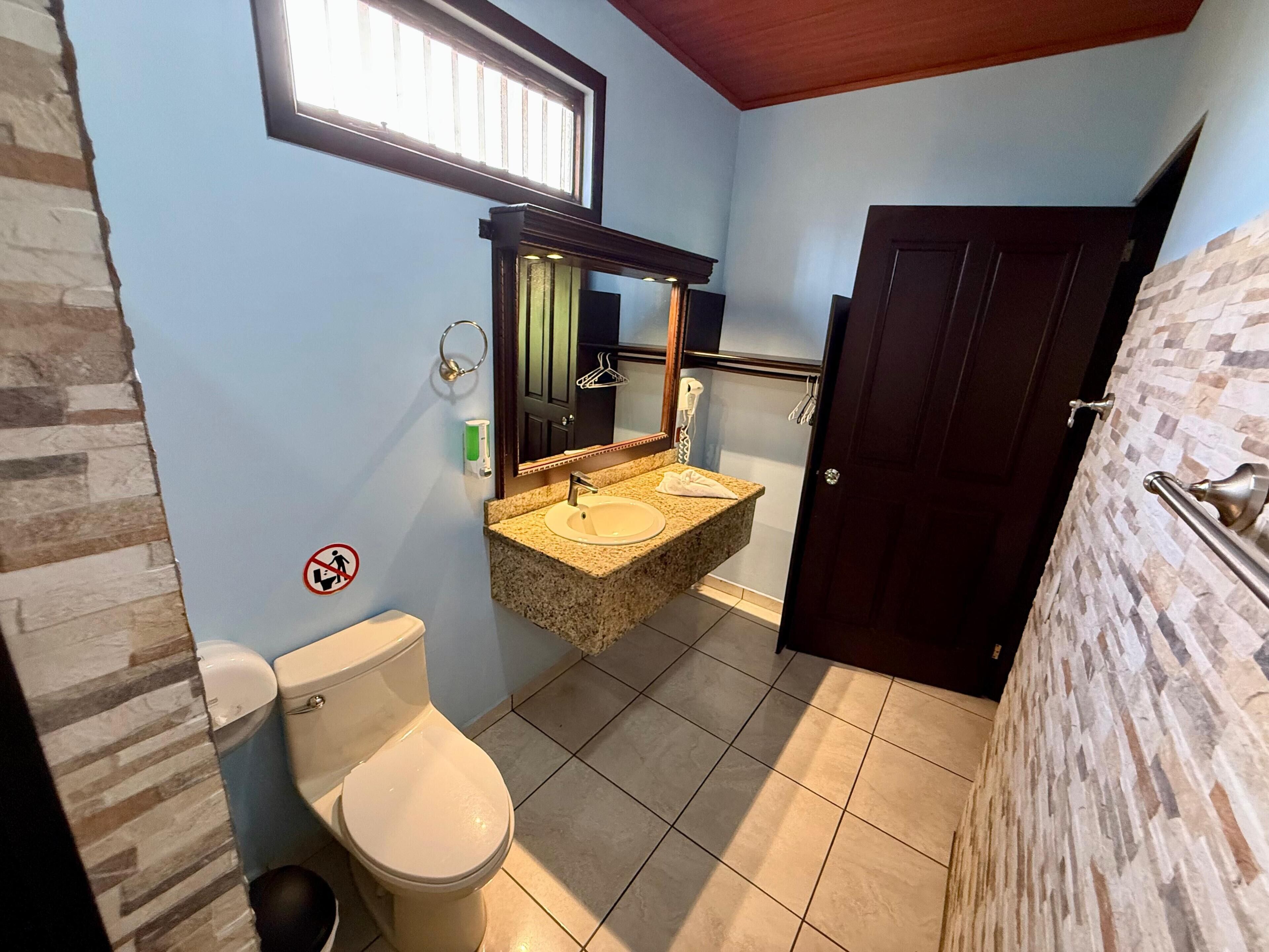 Une salle de bain avec des toilettes, un lavabo et un miroir.