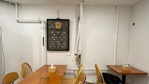 A conference room with a wooden table and chairs, white walls, and visible plumbing. - Insadong R Guesthouse (Seoul)
