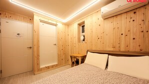 A room with wooden panel walls, a bed with white bedding, a small wooden table, and a mirror. - Insadong R Guesthouse (Seoul)