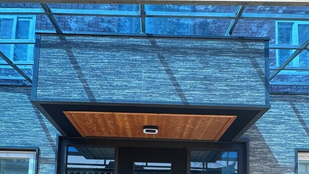 A modern building with a large glass entrance, a wooden overhang, and a statue at the base. - Insadong R Guesthouse (Seoul)