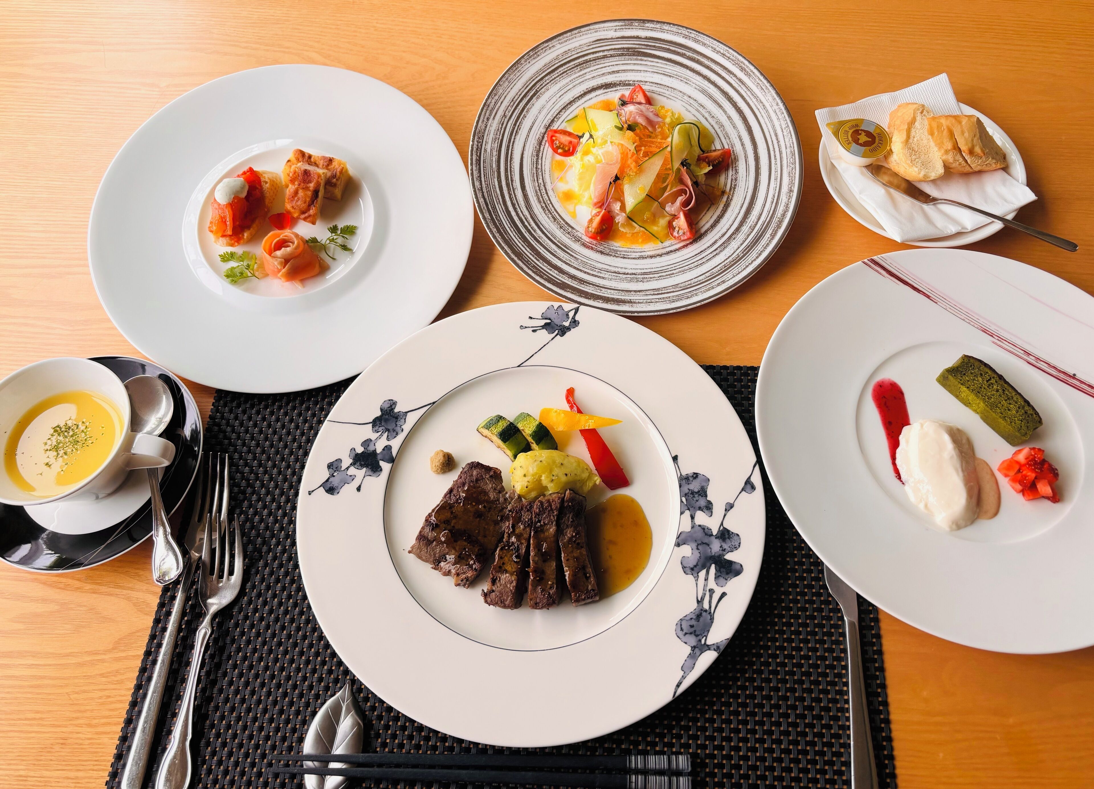A table set with various dishes including meat, vegetables, and a dessert.