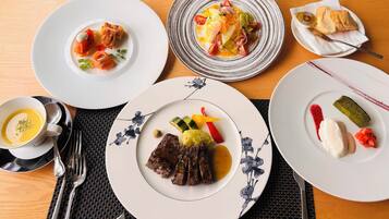 A table set with various dishes including meat, vegetables, and a dessert.