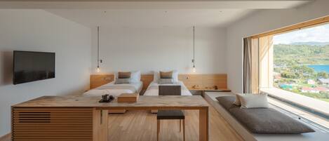 A modern bedroom with a large bed, a desk, and a view of a lake.