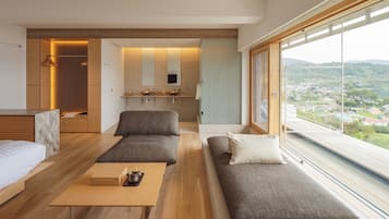 A modern, open-plan living area with a sofa, a coffee table, and a view of a cityscape through large windows.