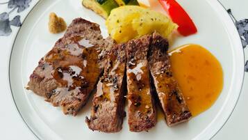 A plate with sliced meat, mashed potatoes, and grilled vegetables.