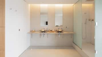 A modern bathroom with two sinks, a large mirror, and a walk-in shower.