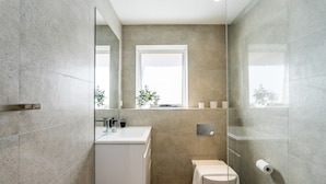 Ein modernes Badezimmer mit einem weißen Waschbecken, einer Toilette und einer Duschkabine aus Glas.