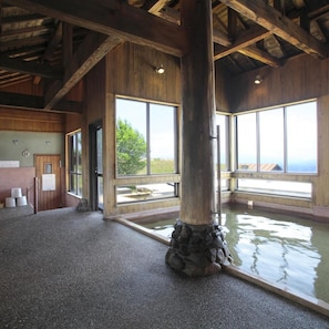 A room with a large wooden beam, a stone base, and a view through large windows.