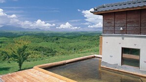 A wooden spa building with a hot spring, surrounded by lush green hills and a clear sky. - Kujukogen Cottage (Taketa)