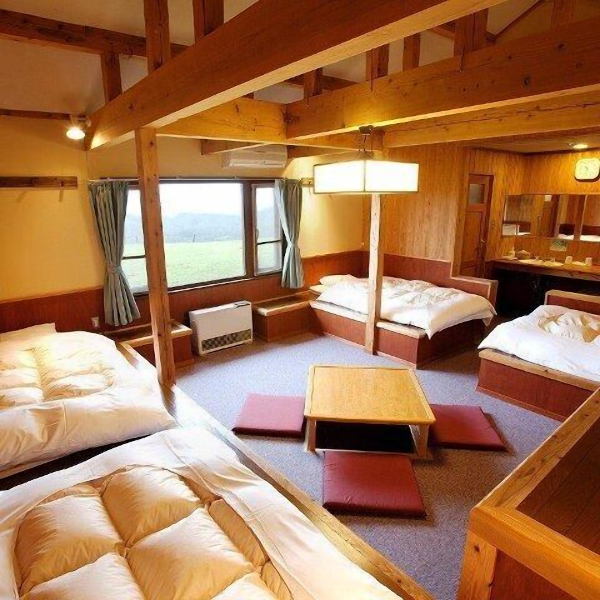 A cabin with three beds, a small table, and a window with curtains.