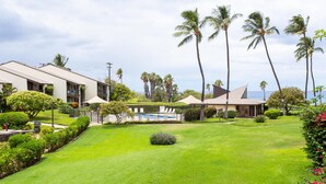 A modern hotel with a pool, surrounded by lush greenery and palm trees.