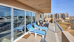 A balcony with sun loungers and a glass door, overlooking a residential area.