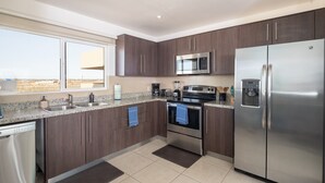 A modern kitchen with dark wood cabinets, stainless steel appliances, and a large window providing a view of the desert landscape.