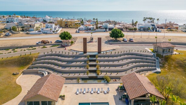 A coastal resort with a central pool, sun loungers, and a view of the sea.